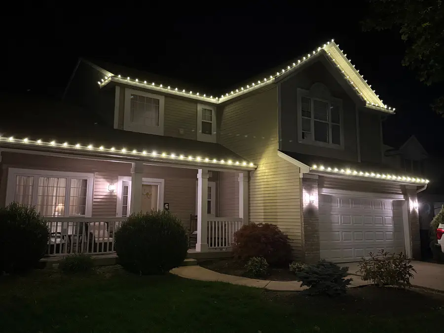 Real Go To Cleaning Christmas light install: warm white C9 lights along the rooflines of a two-story Grand Rapids-area home