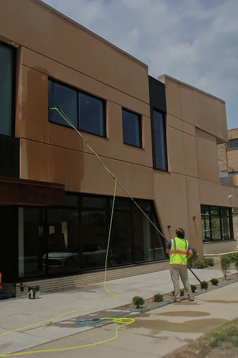 Go To Cleaning technician cleaning upper windows on a commercial building with a water-fed pole