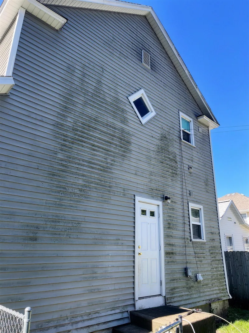 Before: two-story home siding streaked with mildew