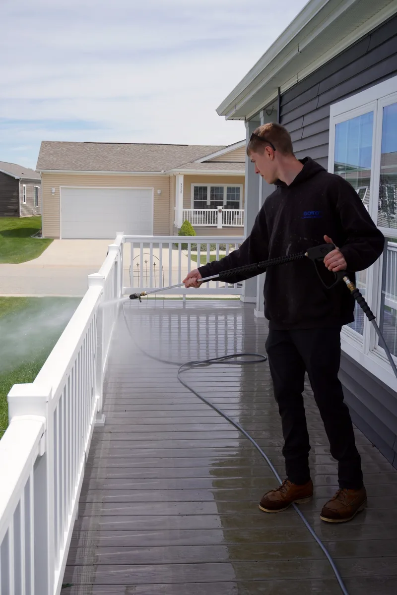 Go To Cleaning technician washing a porch and railing on a Rockford home