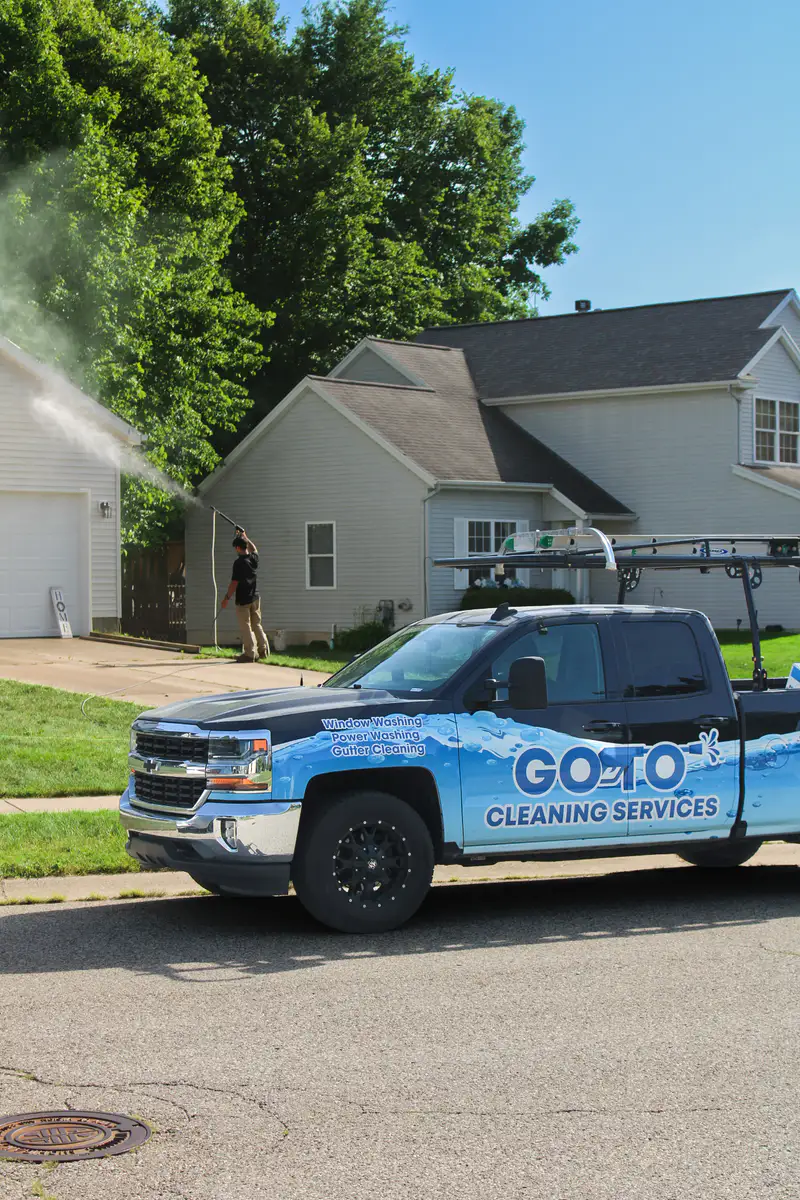 Go To Cleaning crew soft washing a home with the company truck out front